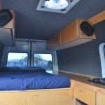DIY Sprinter camper van interior, showing bed, cabinets and cooktop (photo: 3Up Adventures)