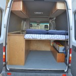 DIY Sprinter camper van interior, showing high rear bed and house battery bank (photo: 3Up Adventures)